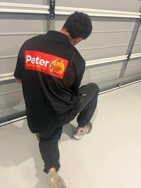 Peter Garage Doors technician servicing the hinges and rollers of a sectional garage door in Brisbane