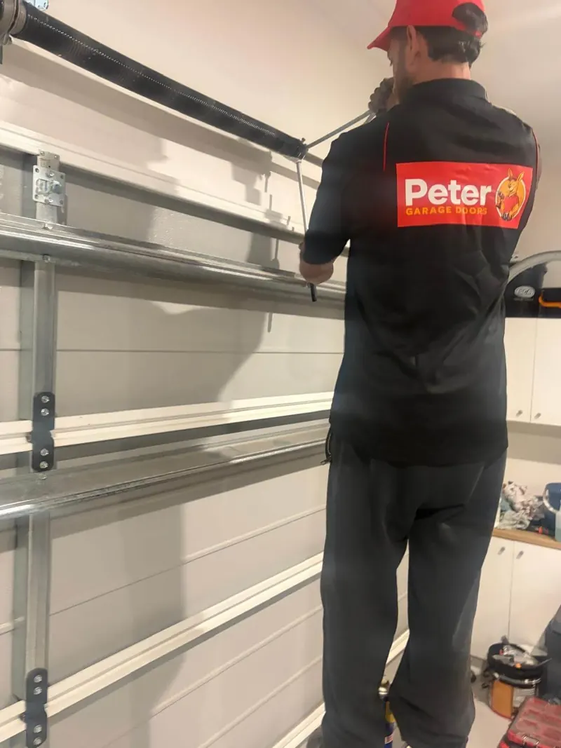 Peter Garage Doors technician winding a new torsion spring on a Brisbane garage door