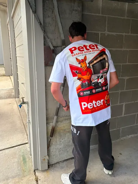 Peter Garage Doors technician repairing the spring on an older tilt garage door during an on-site service call